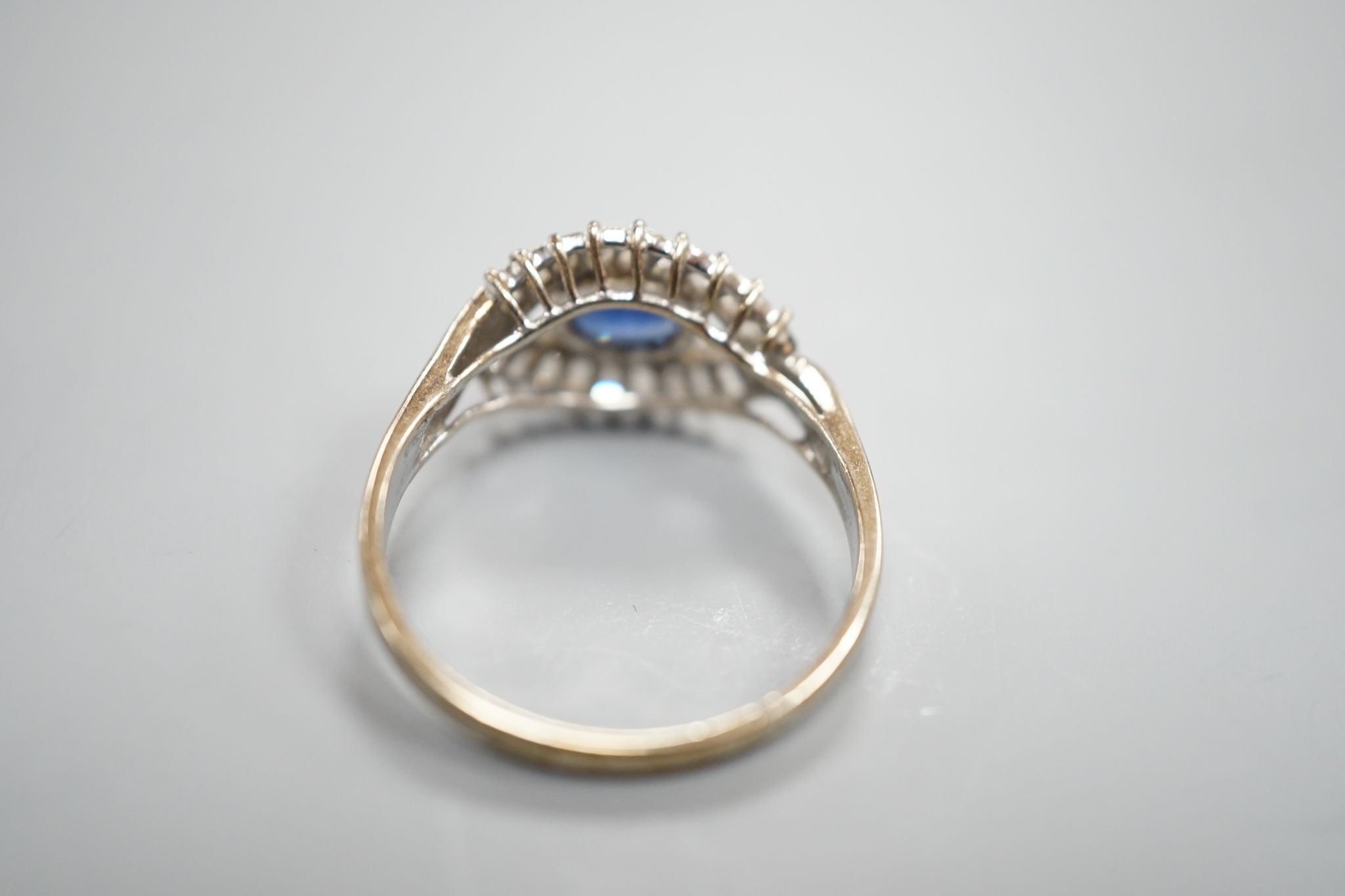 A modern 585 white metal sapphire and baguette cut diamond cluster set 'eye' ring, size T, gross 4 grams.